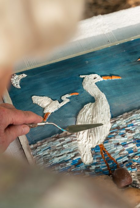 Travail à la spatule sur une mosaïque aux oiseaux
